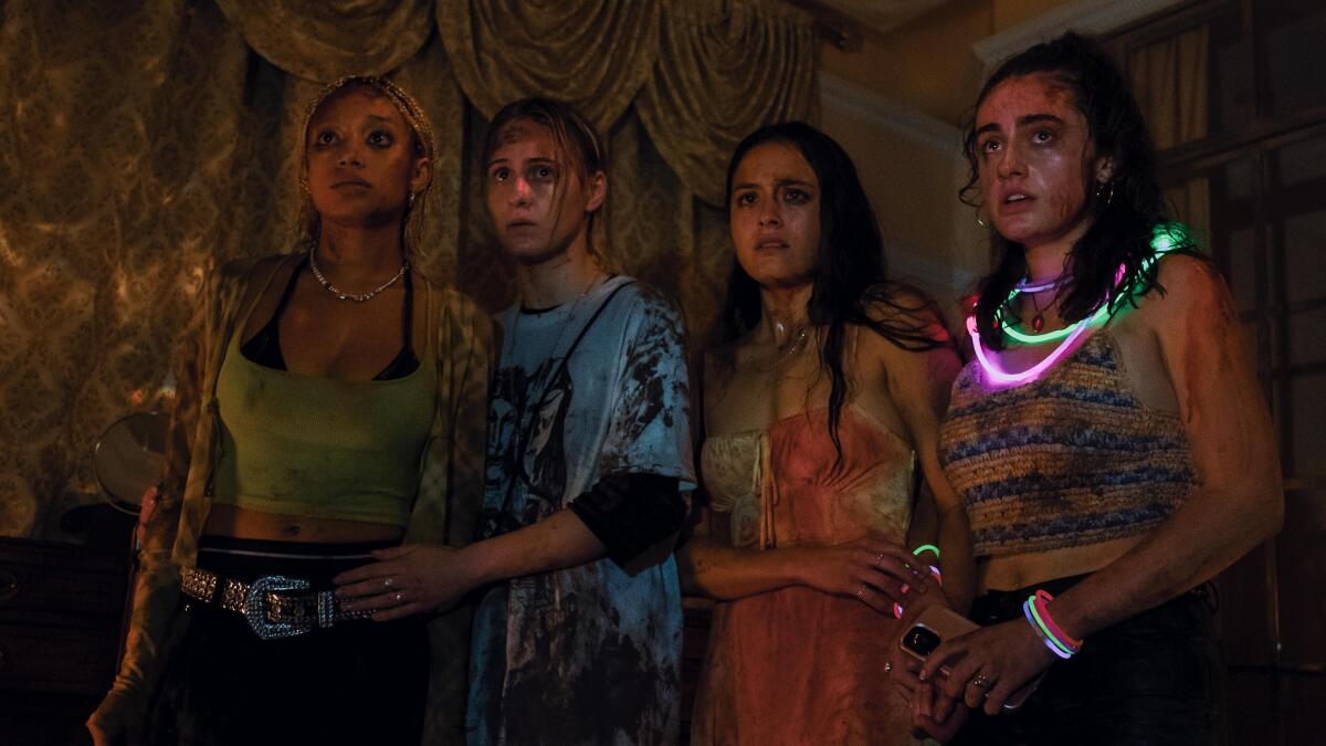 Four women, the one on the right wearing a glowing necklace, stand together in “Bodies Bodies Bodies.”