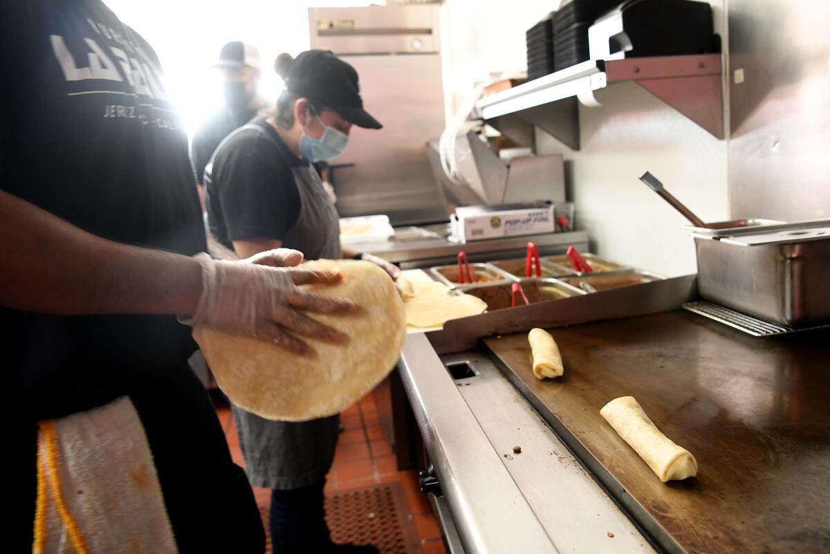 Workers at Burritos La Palma make burritos.