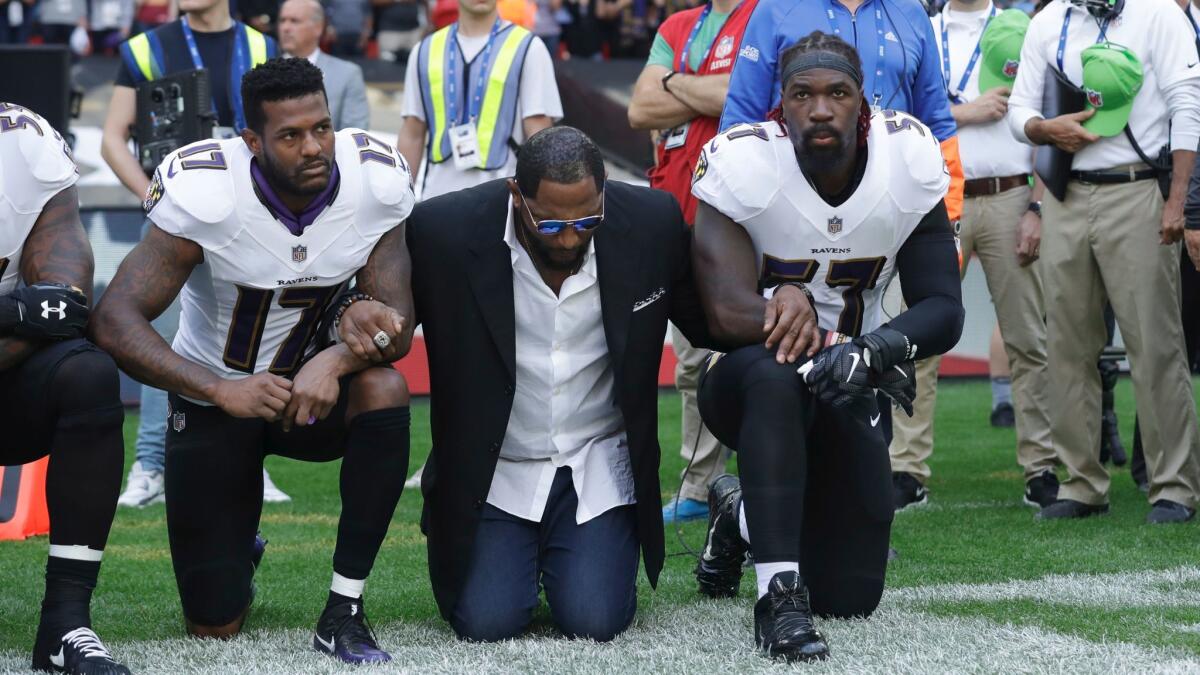 Ray Lewis kneels between Baltimore Ravens wide receiver Mike Wallace, left, and inside linebacker C.J. Mosley on Sept. 24.