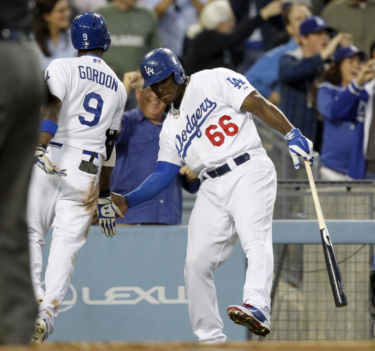 Yasiel Puig congratulates Dee Gordon for hitting a triple and scoring on an error by Colorado Rockies left fielder Charlie Blackmon on Monday.