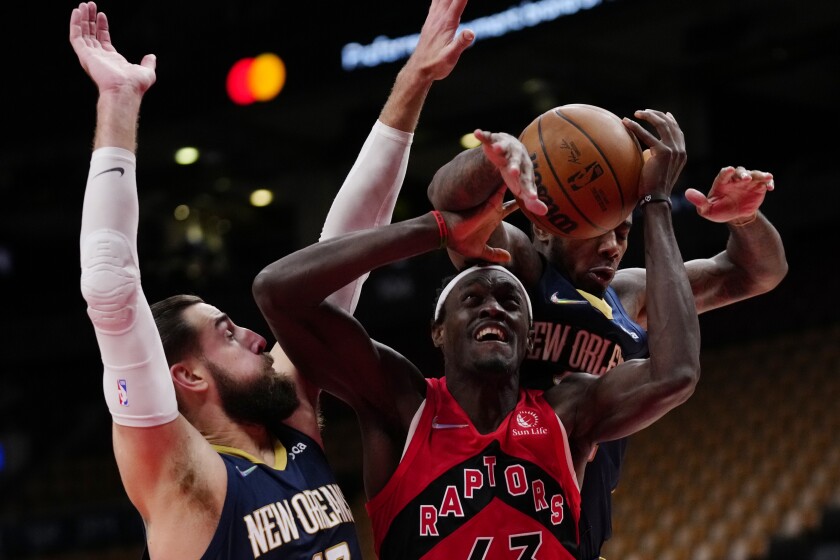 Toronto Raptors forward Pascal Siakam, center, is fouled by New Orleans Pelicans' Gary Clark, right, as Pelicans center Jonas Valanciunas, left, defends during second-half NBA basketball game action in Toronto, Sunday, Jan. 9, 2022. (Frank Gunn/The Canadian Press via AP)