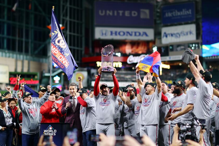 Washington Nationals Manager Dave Martinez hoists the Commissioners Trophy after winning the World Series.