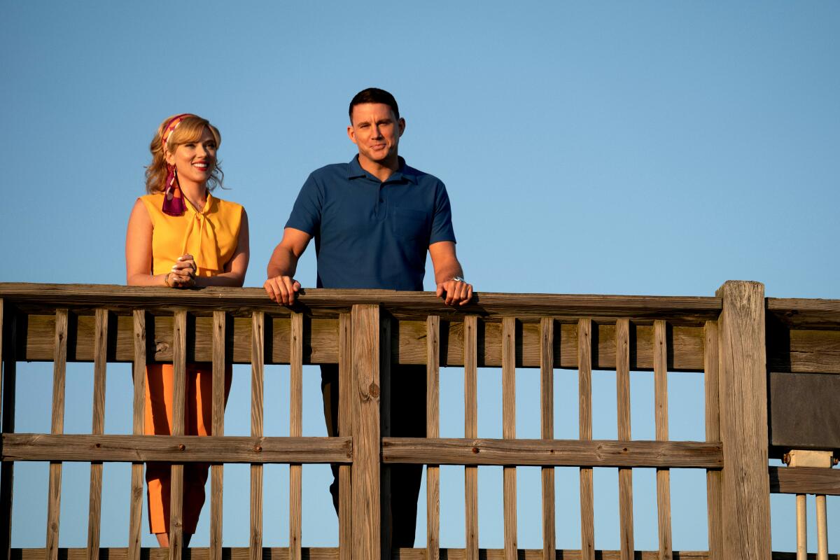 A woman and a man stand on a bridge.