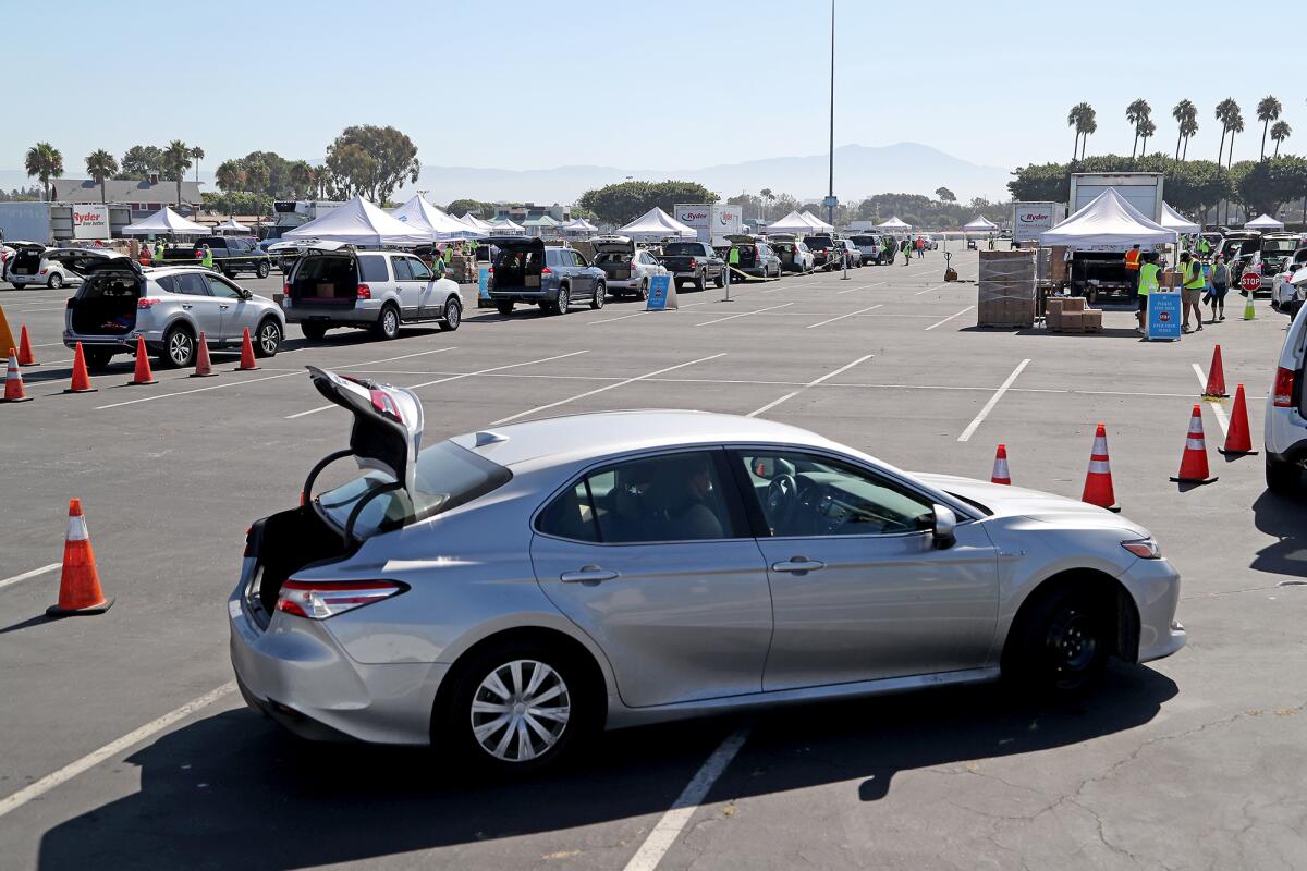 Hundreds of vehicles lineup for free groceries during a drive-through food distribution event at the OC fairgrounds.