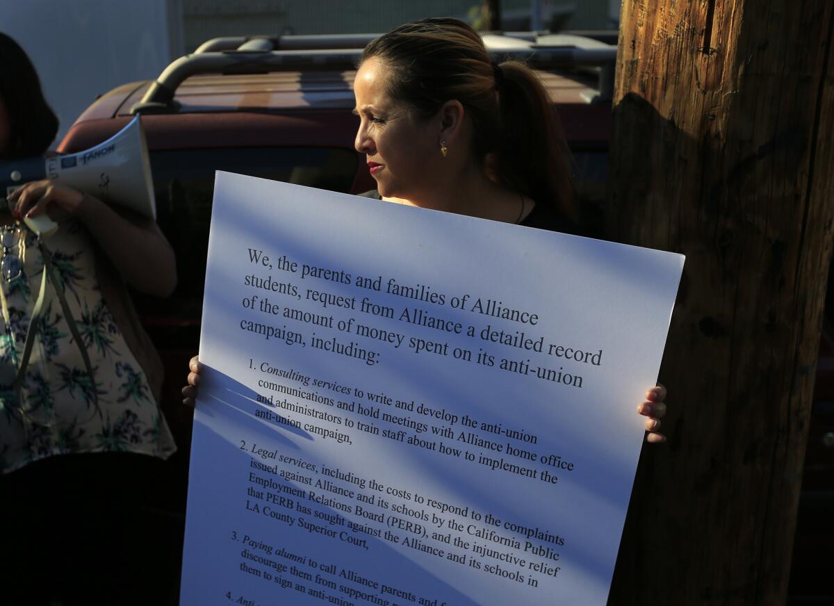 Maria Esparza of Huntington Park, shown outside Alliance Gertz-Ressler Academy High School in Los Angeles last November, holds up a sign detailing parents' concerns about Alliance's handling of unionization efforts.