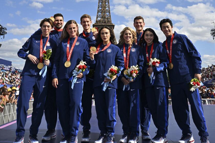 U.S. figure skaters pose at a ceremony in Paris with gold medals won from the 2022 Beijing Olympics