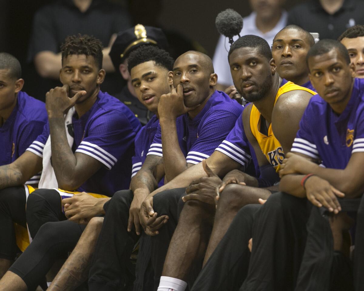 Lakers guard Kobe Bryant, center, sits on the bench with teammates during the fourth quarter of Sunday's preseason opener in Honolulu.