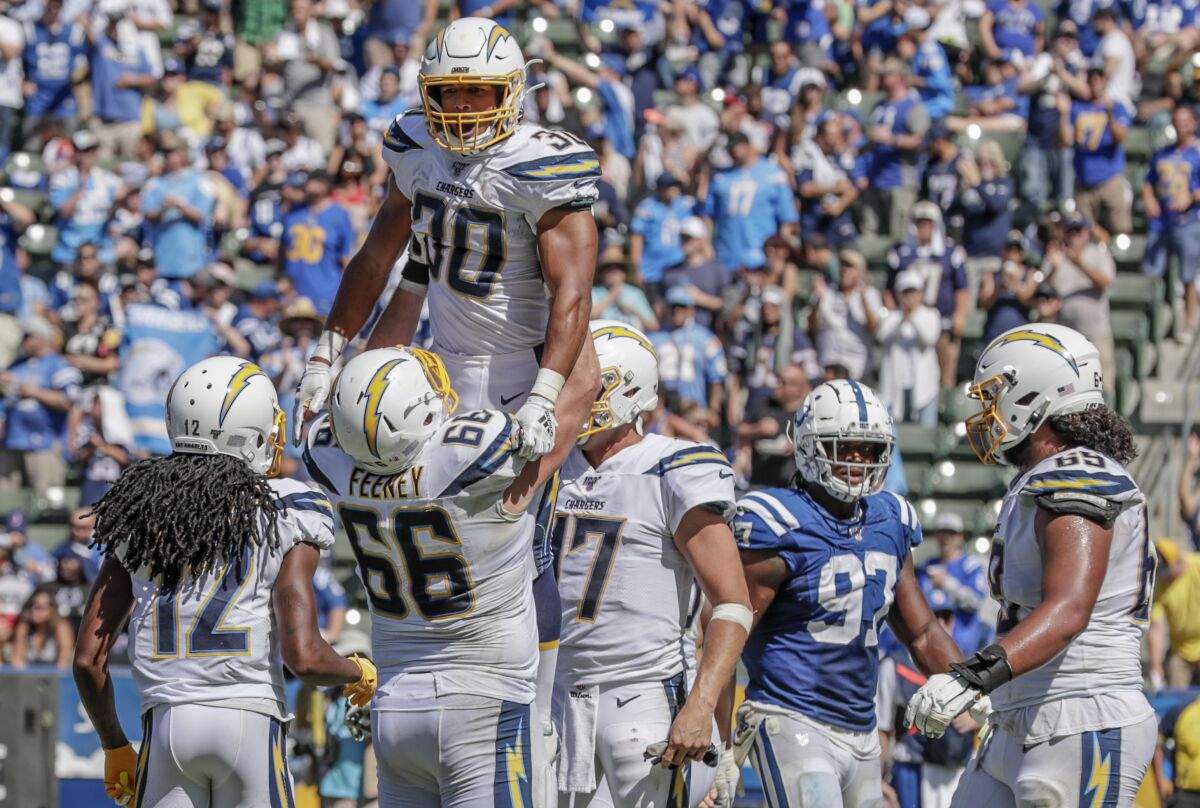 Chargers running back Austin Ekeler is hoisted by teammate Dan Feeney after scoring on a 55-yard touchdown catch Sunday.