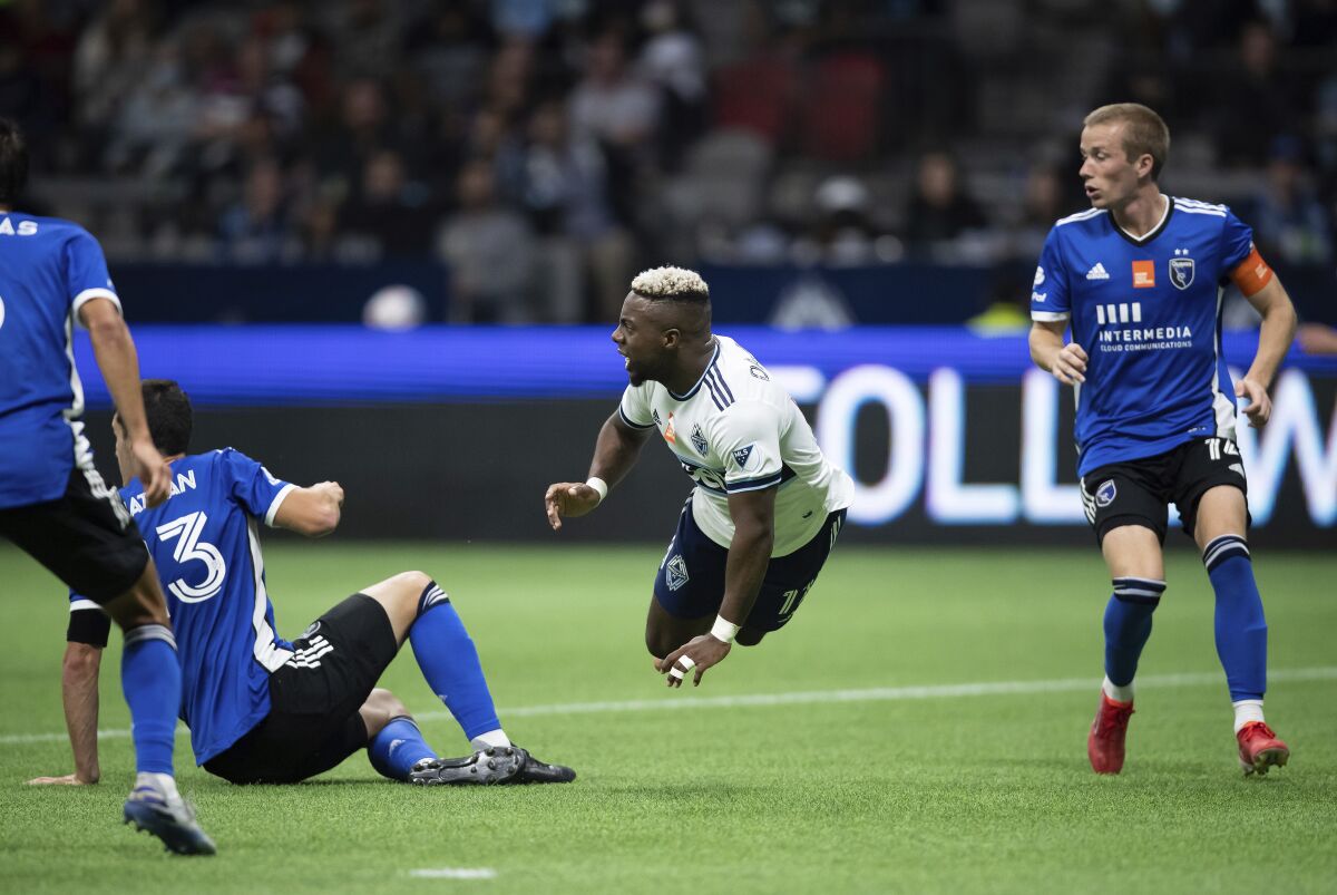Vancouver Whitecaps' Cristian Dajome, center, is upended by San Jose Earthquakes' Nathan Brazil, left, as Jackson Yueill watches during the second half on an MLS soccer match, Saturday, Oct. 2, 2021 in Vancouver, British Columbia. (Darryl Dyck/The Canadian Press via AP)