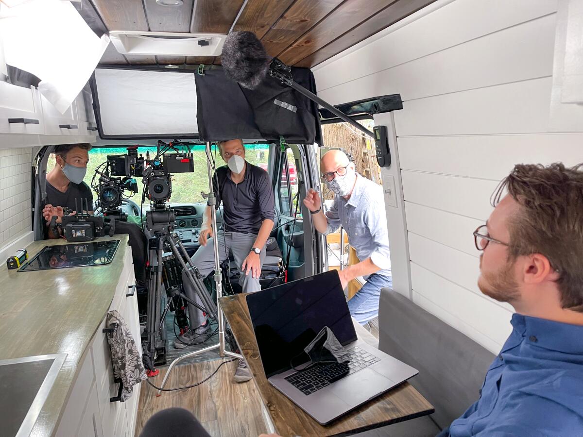 "Eat the Rich" director Theo Love enters the van of Joe Fonicello, right, during filming of Netflix's GameStop series.