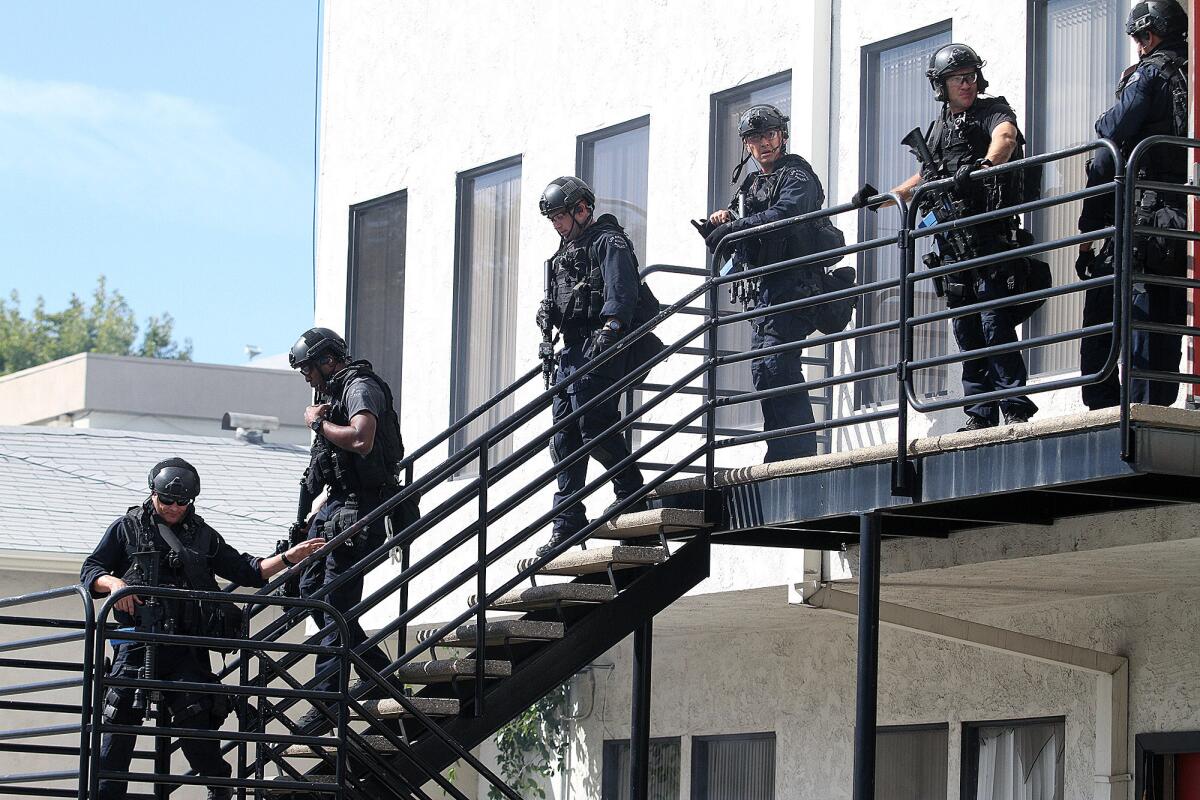 With the situation neutralized, a stream of LAPD SWAT officers exit a vacant building on the 3400 block of Alameda Avenue in Burbank where the Los Angeles Police Department's SWAT officers practiced tactic exercises on Thursday, October 23, 2015. The exercise, which included explosions and flash-bang detonations, were conducted throughout the morning and into the afternoon.