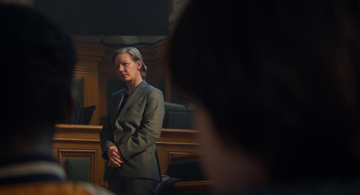 A woman on trial stands in the courtroom.
