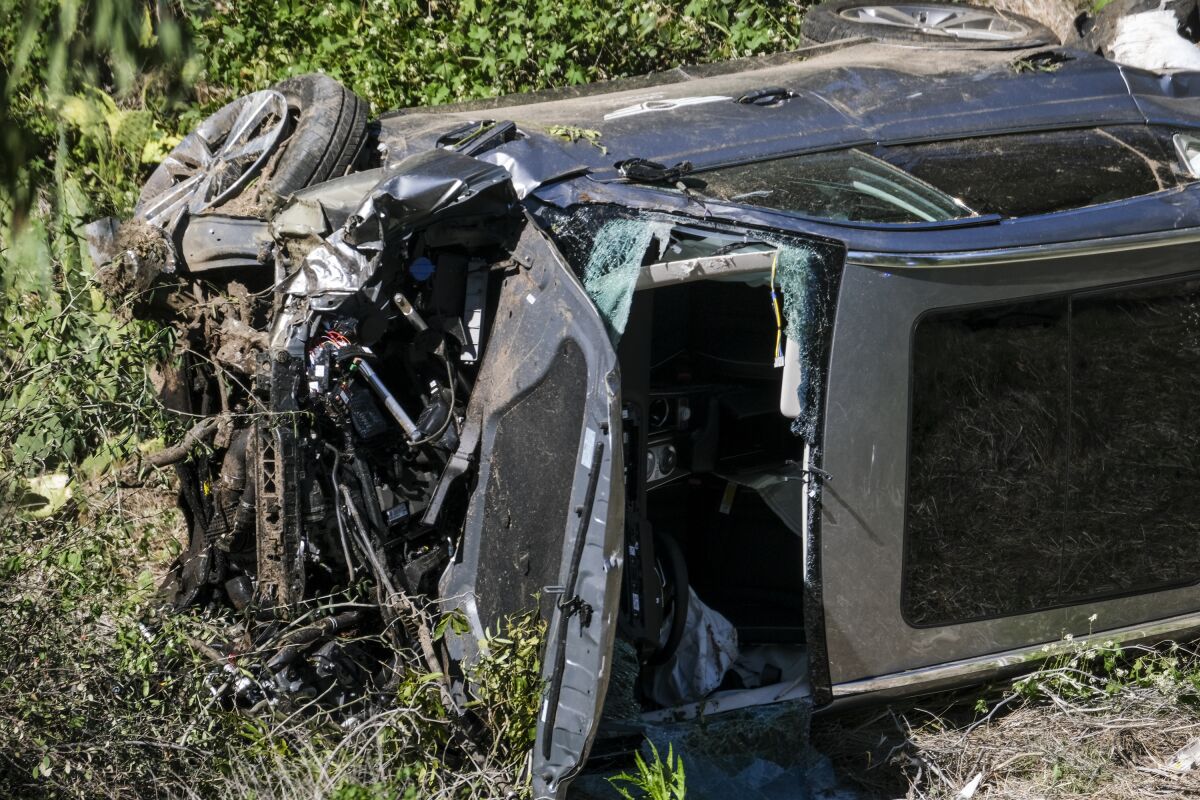 A vehicle with extensive front-end damage and its windshield removed rests on its side after an accident.