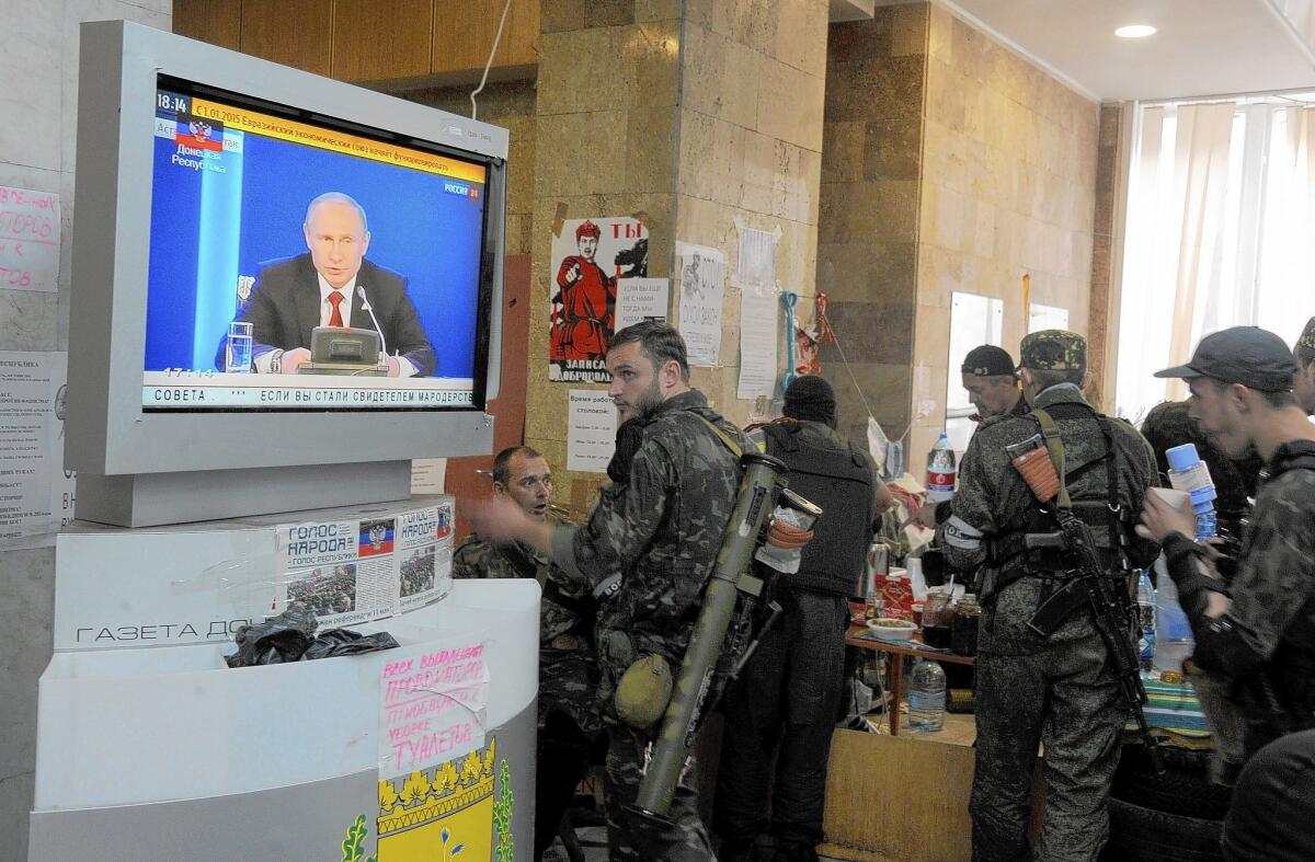 Pro-Russia fighters listen as a speech by Russian President Vladimir Putin is shown on television in a government building in Donetsk, in eastern Ukraine.