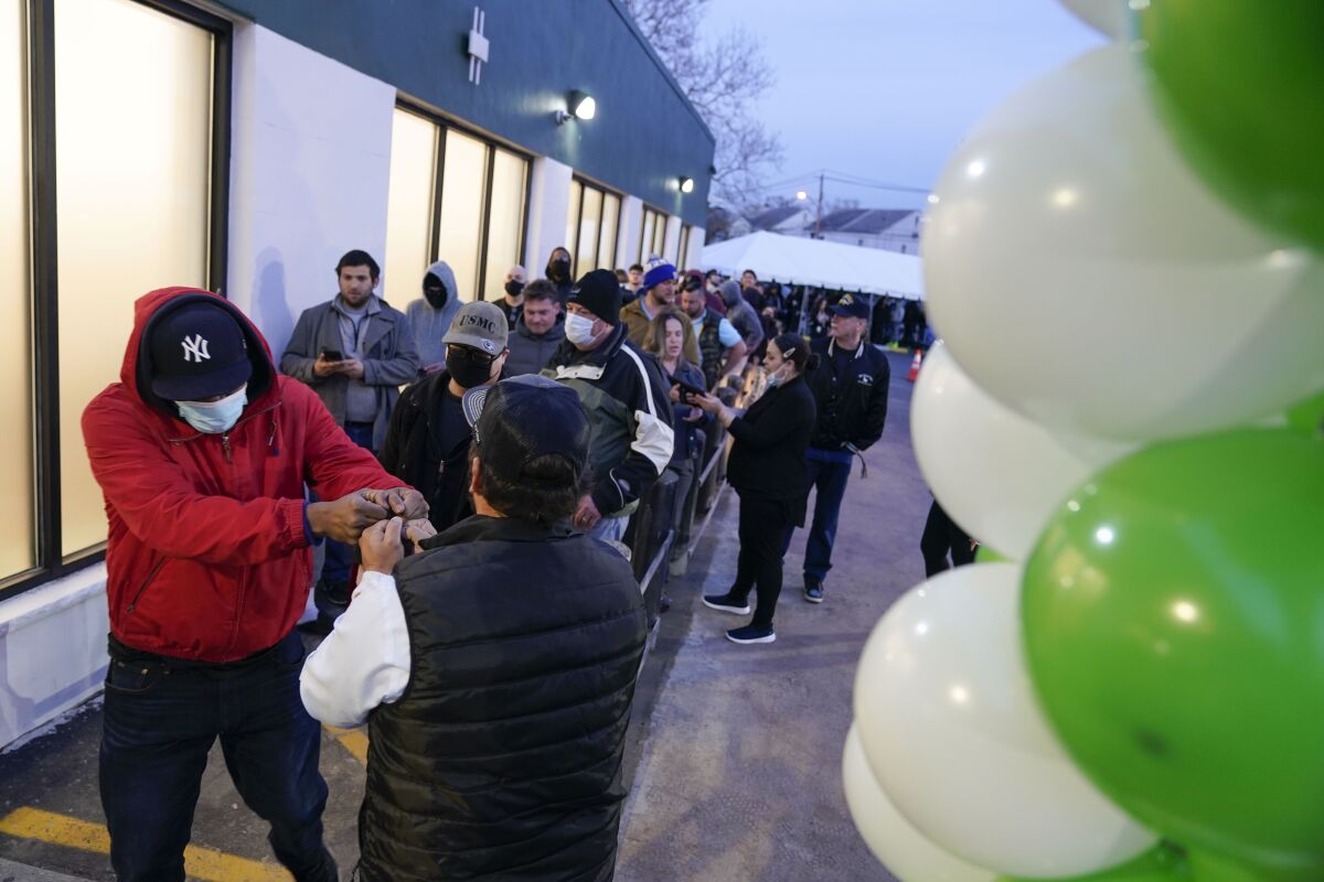 People wait in line outside a business next to balloons