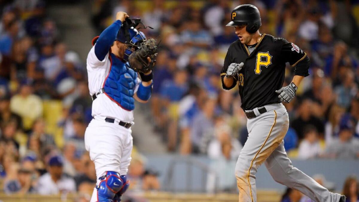 Pirates infielder Jordy Mercer scores on his solo home run as Dodgers catcher Yasmani Grandal stands at the plate during the seventh inning of a game on Aug. 12.