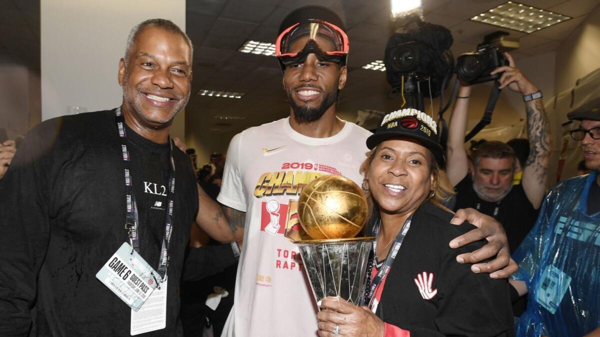 Raptors forward Kawhi Leonard poses for a photo with his uncle, Dennis Robertson, and mother, Kim Robertson, holding the NBA Finals MVP trophy.