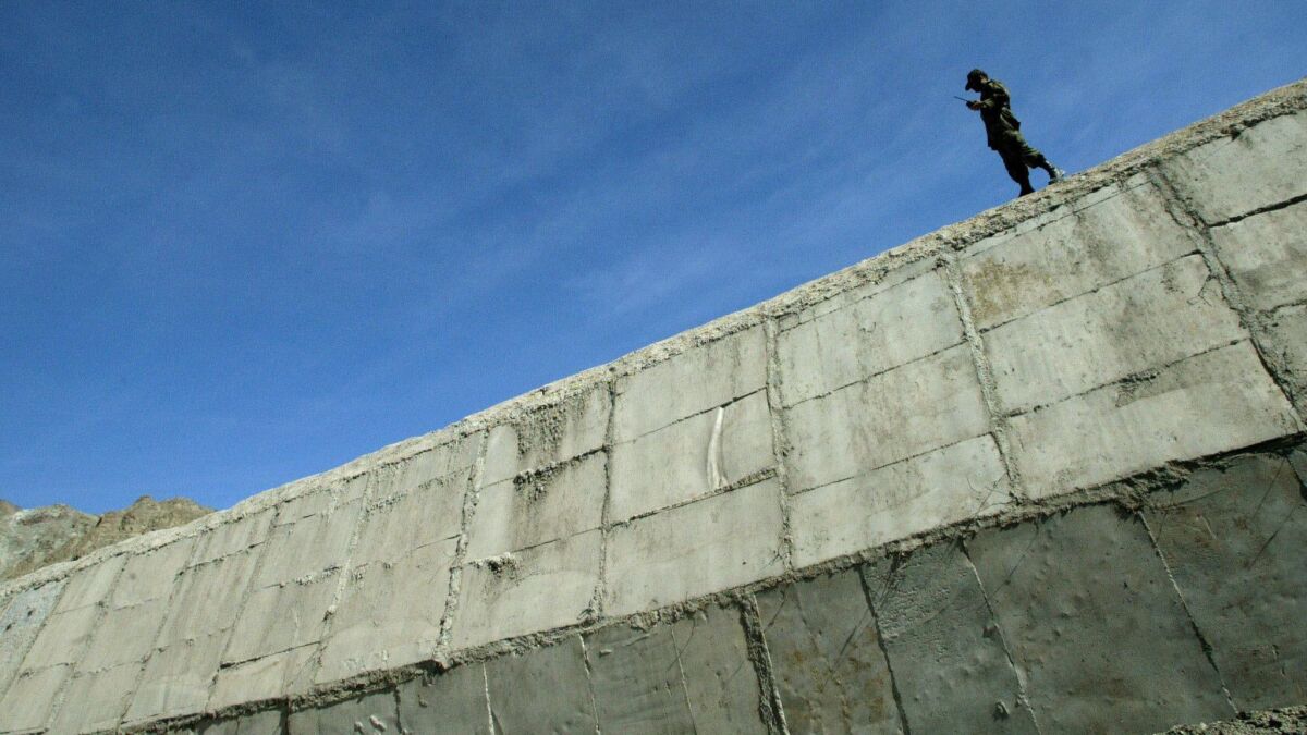An Iranian soldier stands guard in 2003 at a wall built to prevent drug trafficking in the Mirjaveh point where the borders of Iran, Afghanistan and Pakistan meet.