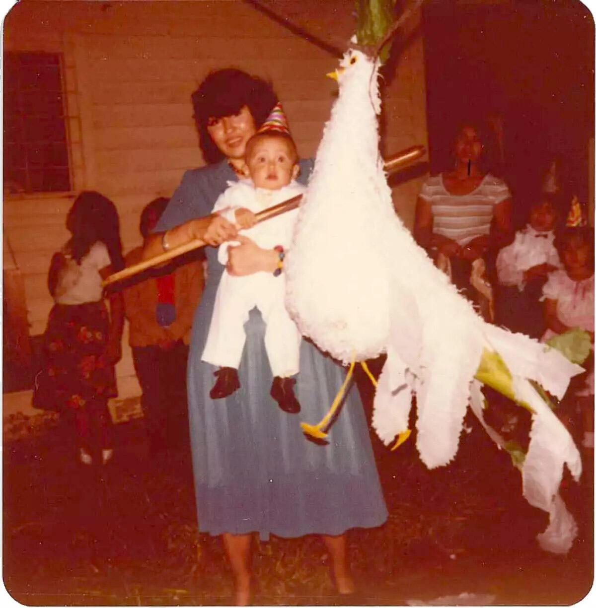 Gustavo and his mom as she holds a stick near a large bird-shaped figure.
