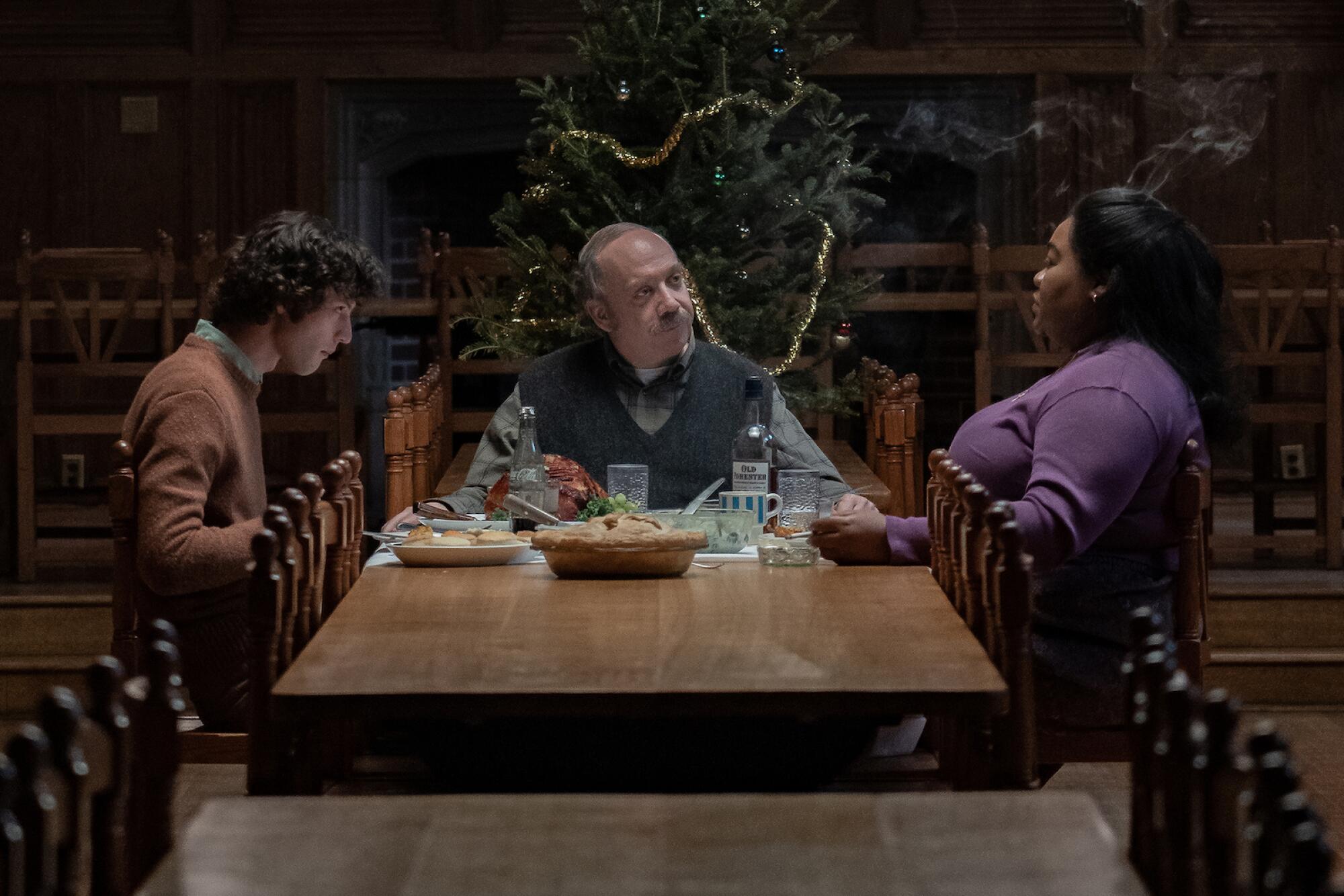 Three people sit around a dining table at Christmas time.