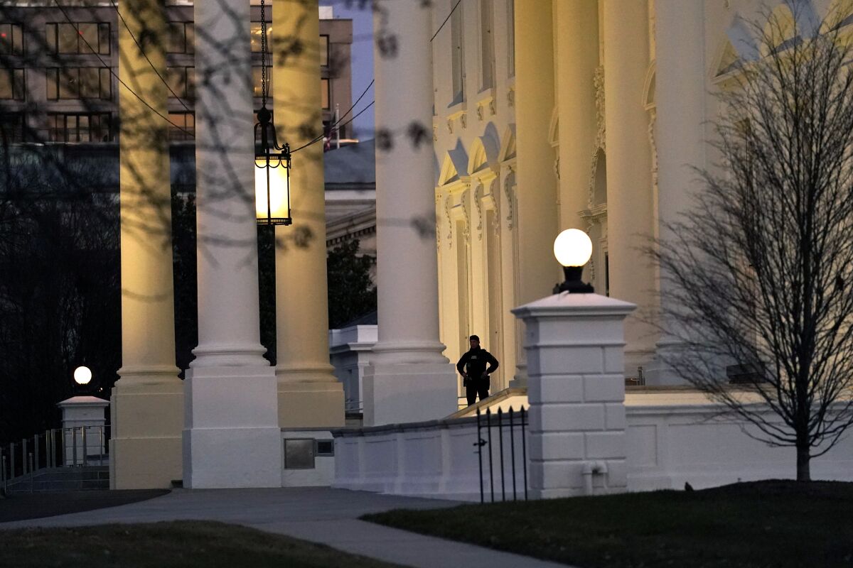 A U.S. Secret Service guard stands post at the lit-up North Portico of the White House on Wednesday.