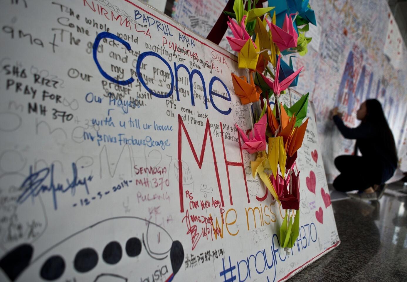 A Malaysian girl writes a message expressing prayers and well-wishes for passengers onboard missing Malaysia Airlines (MAS) flight MH370 at Kuala Lumpur International Airport in Sepang on March 17, 2014.