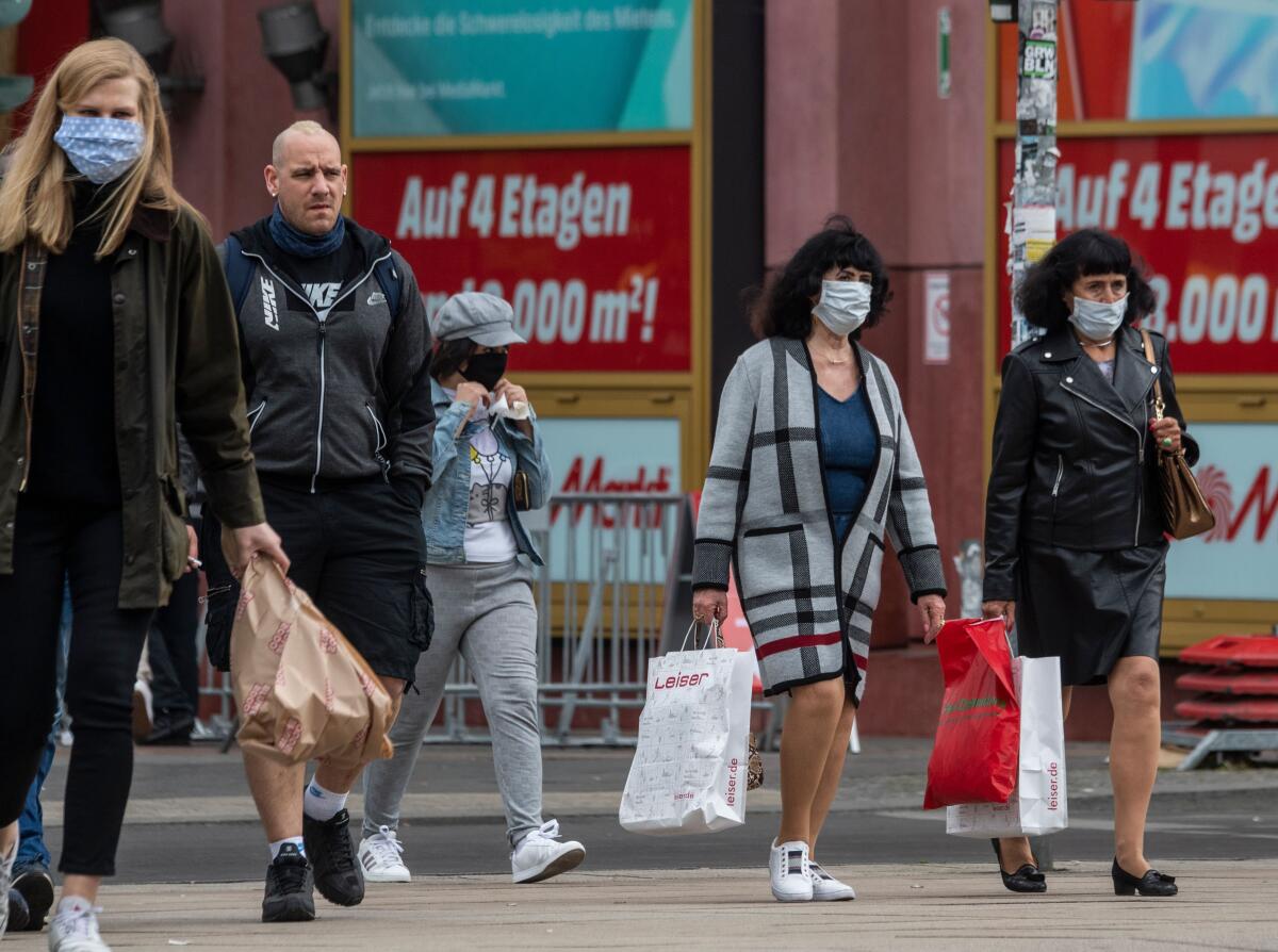 Shoppers wearing face masks walk out of a shopping mall in Berlin