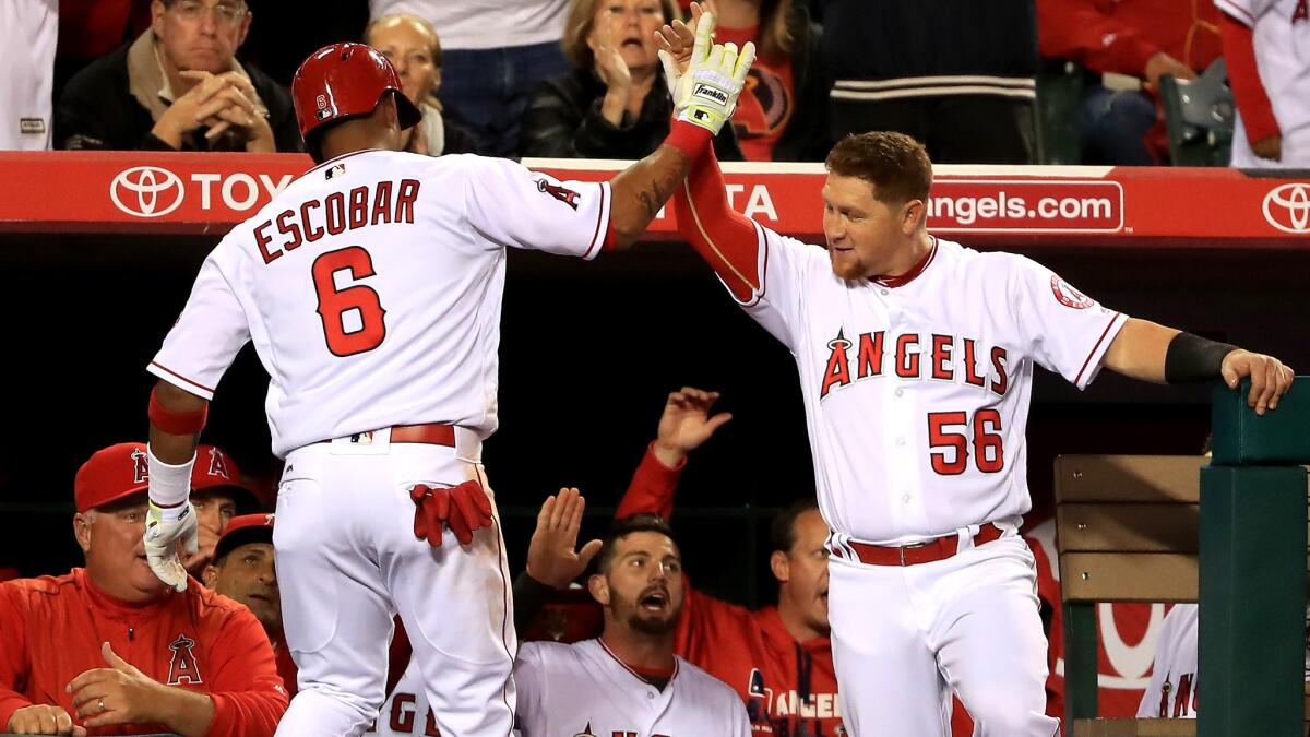 Angels shortstop Yunel Escobar (6) is congratulated by teammate Kole Calhoun (56) ater hitting a solo home run against the Rangers during the third inning Thursday.