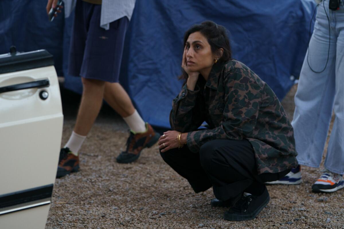 A woman squats in thought on a film set.