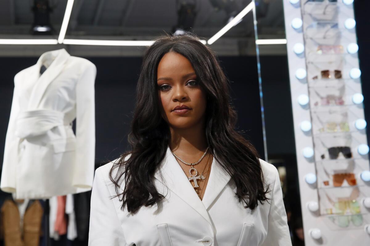 Rihanna posing in a white suit with a gold necklace