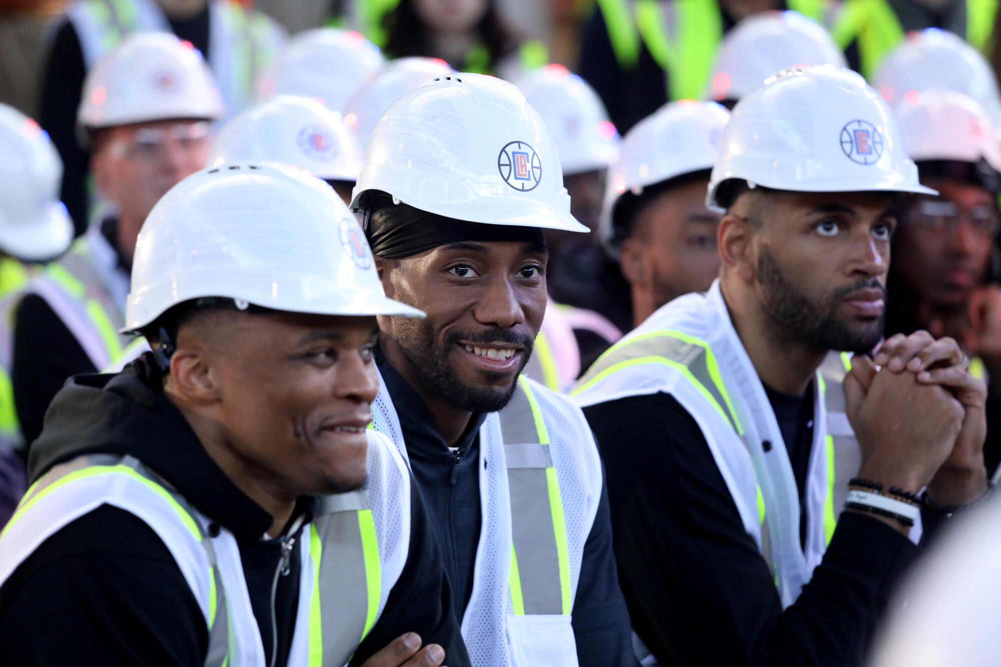 Russell Westbrook ve Kawhi Leonard, Intuit Dome'daki töreni koltuklarından izlerken gülümsüyorlar.