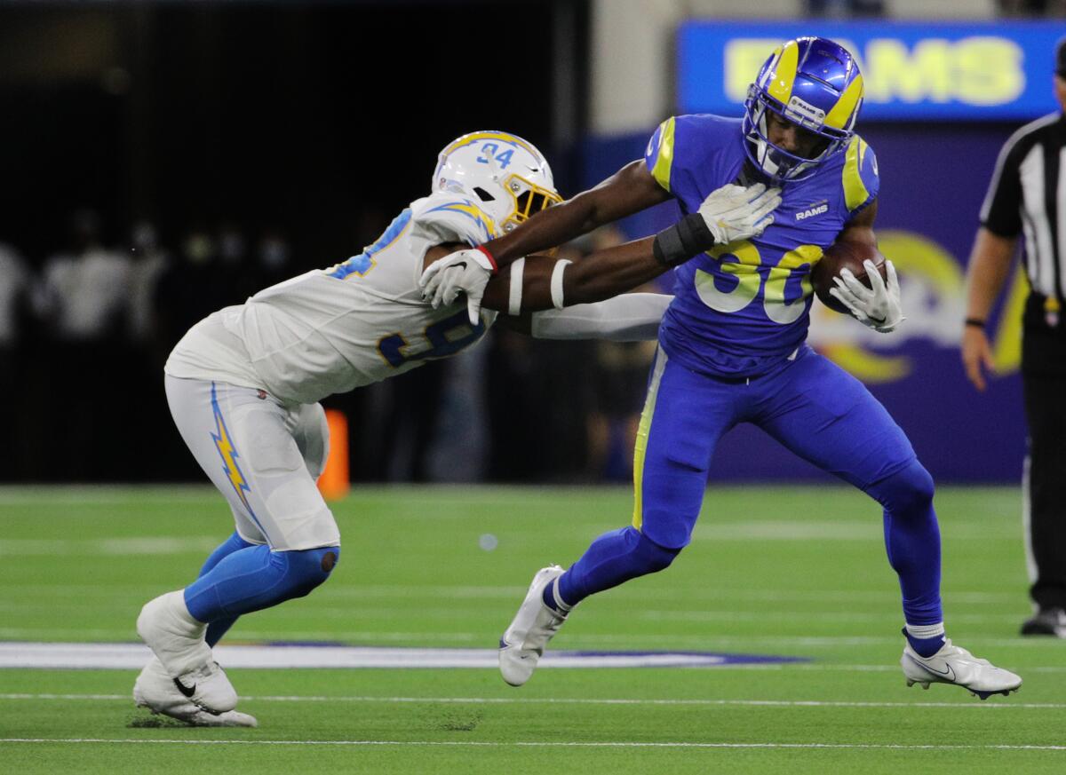 Rams running back Raymond Calais tries to evade the tackle attempt by Charger Chris Rumph II in their preseason opener.