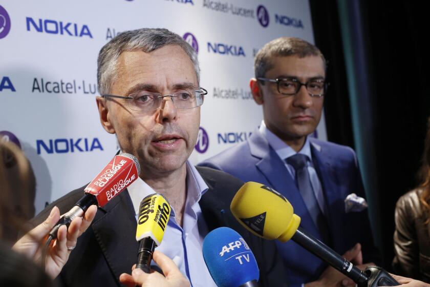 Alcatel-Lucent Chief Executive Michel Combes, left, and Nokia Chief Executive Rajeev Suri announce Nokia is buying its French rival.