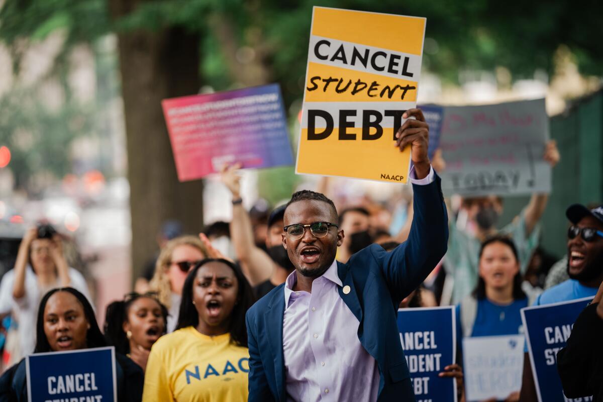 Protesters hold signs reading "Cancel Student Debt."