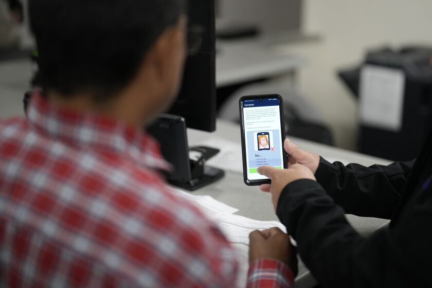 ARCHIVO - Un agente ayuda a configurar un teléfono que será utilizado para rastrear a un hombre en unas instalaciones de procesamiento de inmigrantes, el 15 de marzo de 2023, en San Diego. (AP Foto/Gregory Bull, archivo)