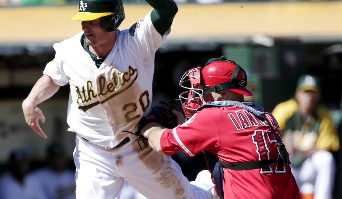 A's third baseman Josh Donaldson (20) is tagged out at the plate byAngels catcher Chris Iannetta while trying to score on a flyout by Derek Norris in the fourth inning Wednesday afternoon in Oakland.