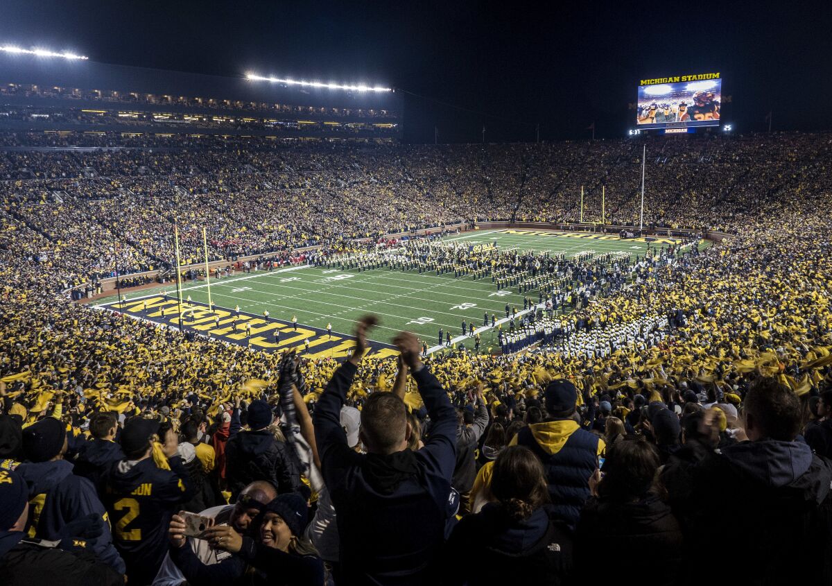 FILE - Fans cheer as the Michigan team takes the field at Michigan Stadium for an NCAA college football game against Wisconsin in Ann Arbor, Mich., Oct. 13, 2018. Michigan's Big House will be sitting empty when the leaves start to change this fall. From Ann Arbor to Los Angeles to Oxford, that most American of pursuits, college football, has either given up hope of getting in a traditional season or is flinging what amounts to a Hail Mary pass in a desperate attempt to hang on in the age of COVID-19. (AP Photo/Tony Ding, File)