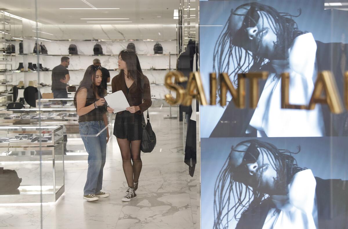 OCC fashion students Jasmine Gonzalez and Elsie Walker, from left, observe a Saint Laurent in South Coast Plaza.