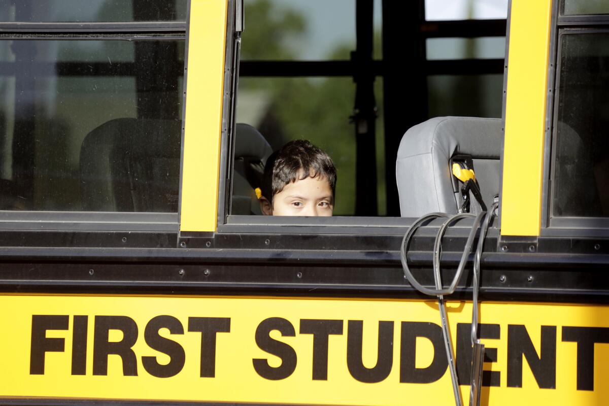 A student peers through the broken window of a school bus that was in an accident involving a Metro train crossing arm Tuesday morning at 55th Street and Long Beach Avenue in South Los Angeles.