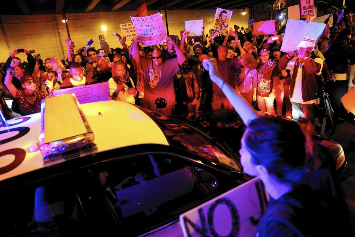 Protesters surround an LAPD vehicle during a second night of demonstrations in Los Angeles over the decision by a Missouri grand jury to not indict a police officer in the killing of an unarmed man.