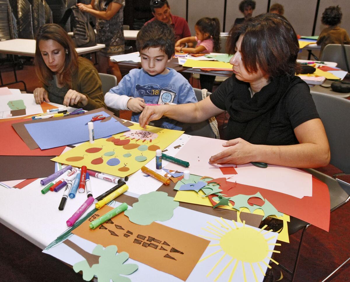 Left to right making collages are Sandy Gililand, Arno Asatryan, 6, and his mother Arus Sargsyan at the It's Big! Draw together Glendale event at the Central Library in Glendale on Saturday, Oct. 19, 2013. Children and adults made collages from construction paper and pasted these on a large and long piece of butcher paper that will be displayed at the library.