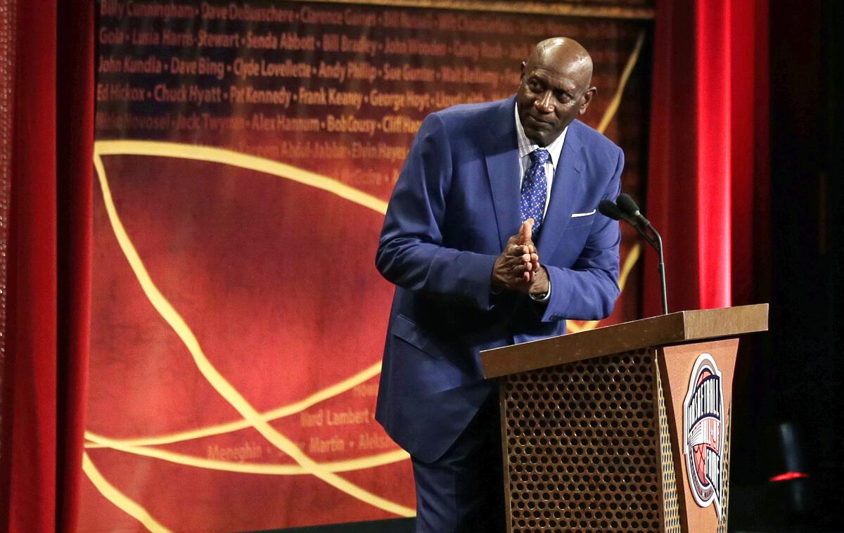 Spencer Haywood thanks Charles Barkley, pictured above him on a screen, at the 2015 Basketball Hall of Fame ceremony.