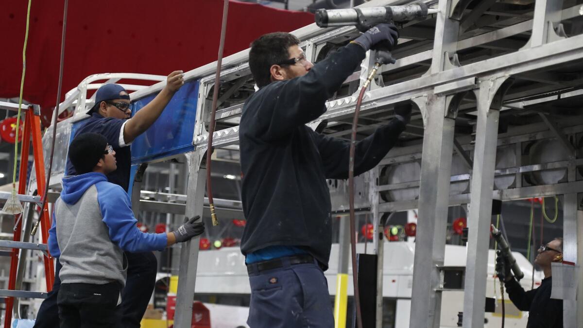 Workers build an electric bus at the BYD production facility in Lancaster this year. California gained a net 6,600 manufacturing jobs in October.