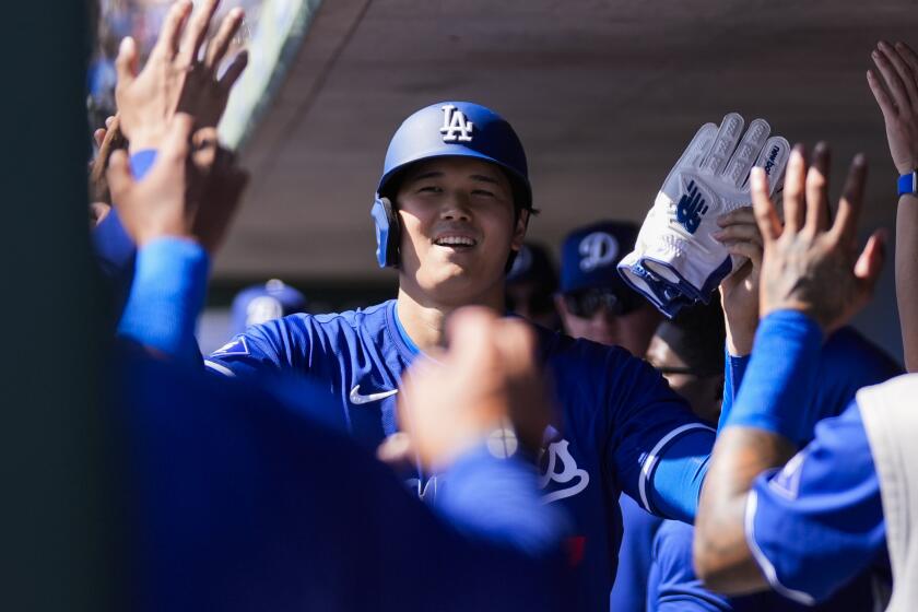 Los Angeles Dodgers designated hitter Shohei Ohtani celebrates in the dugout after scoring.