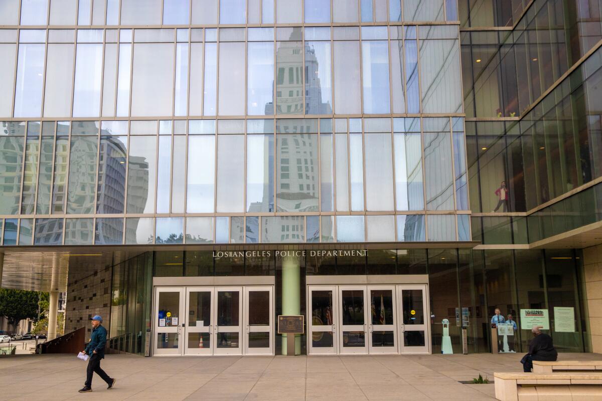 Los Angeles City Hall reflected in a building above the words "Los Angeles Police Department" and several entry doors
