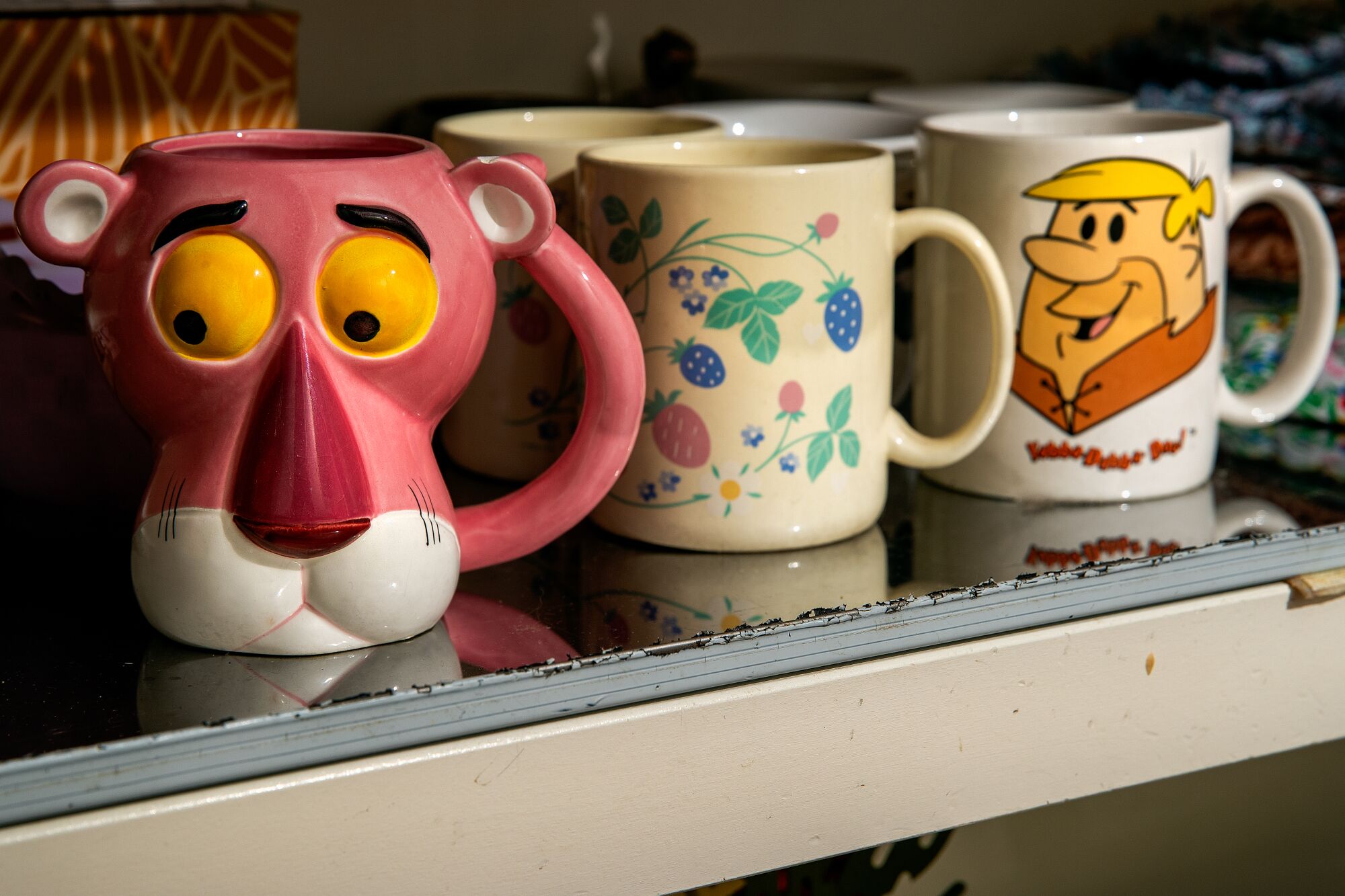 Coffee mugs purchased from estate sales are situated on a shelf inside the kitchen of Amy Solomon's home in Glendale.
