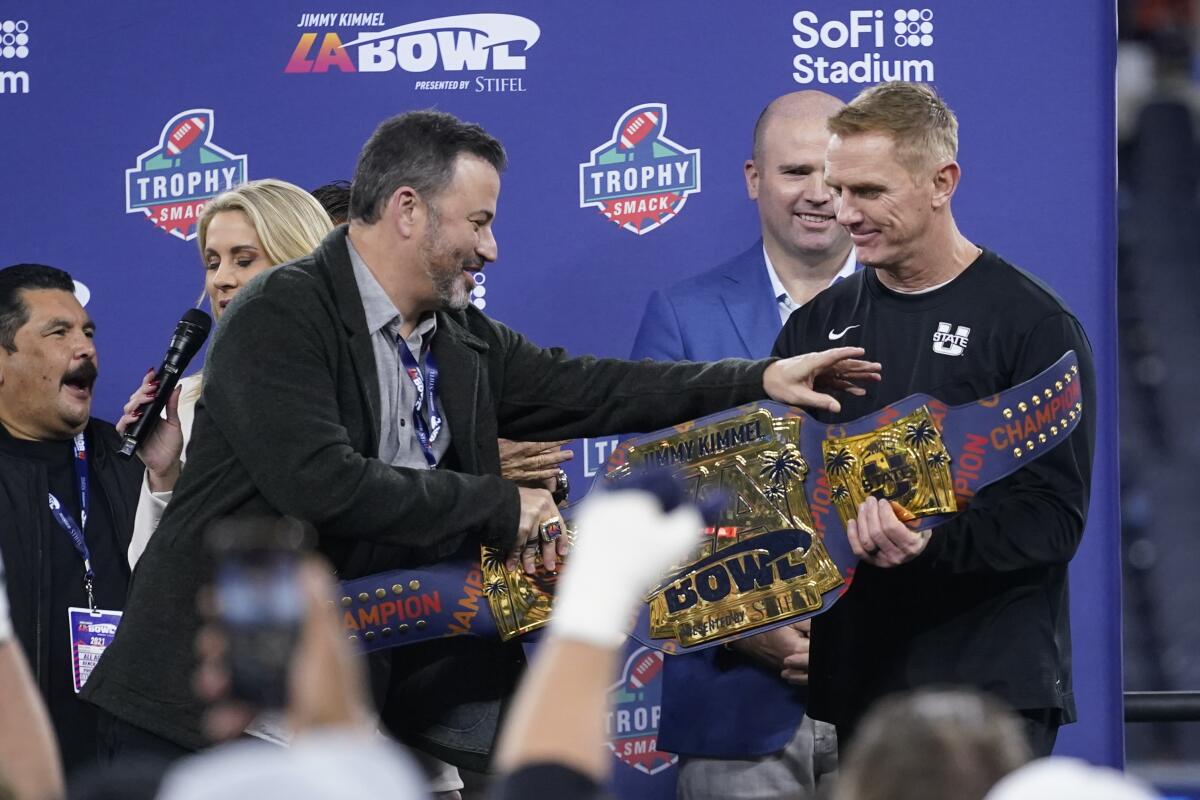 Jimmy Kimmel, left, presents Utah State coach Blake Anderson with a championship belt after the Aggies' win.