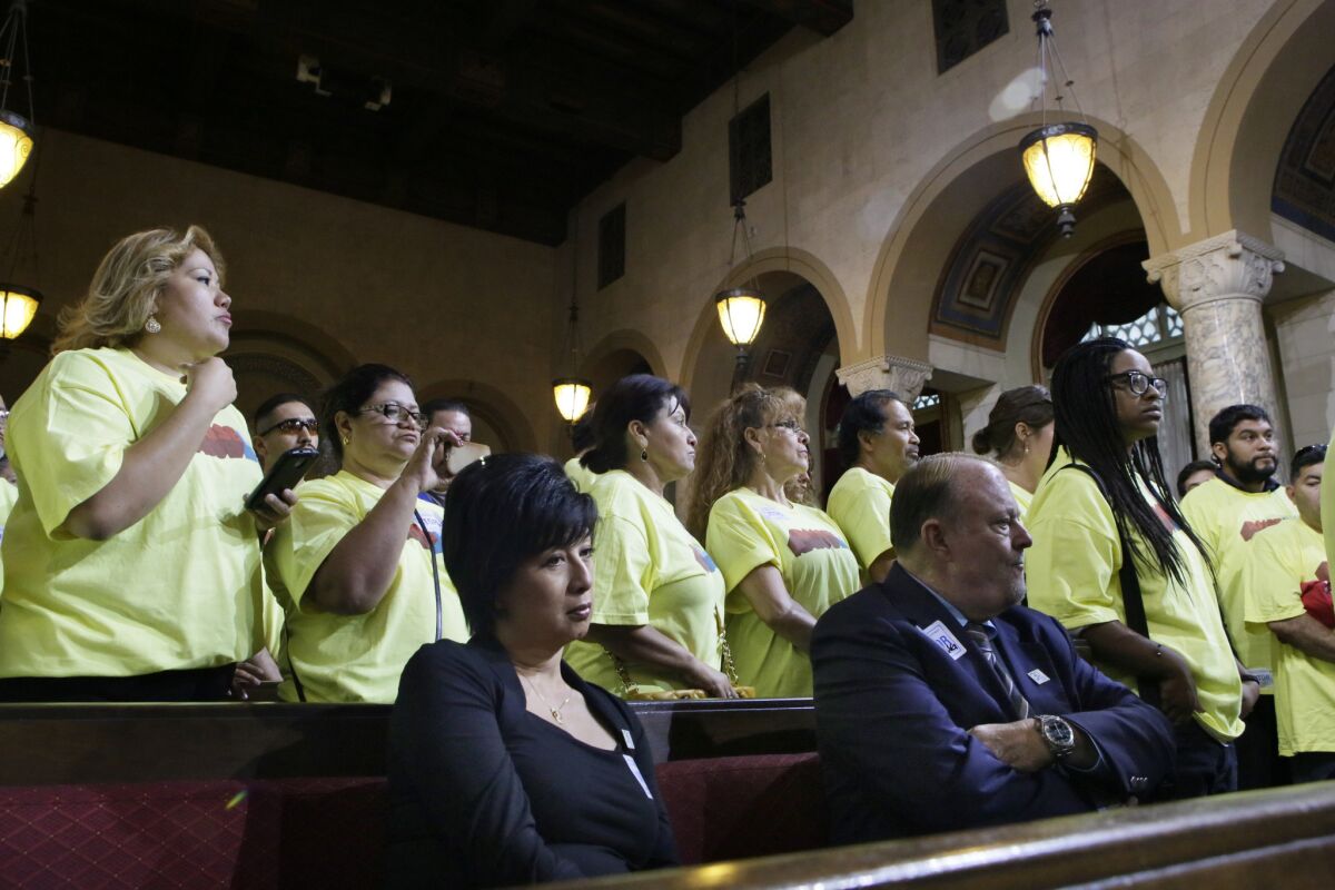 Jim Dunn, foreground right, owner of Airtel Plaza Hotel, who opposes the minimum wage bill, is outnumbered by supporters in yellow shirts when the L.A. City Council tentatively approved a $15.37-per-hour minimum wage for workers at big hotels.