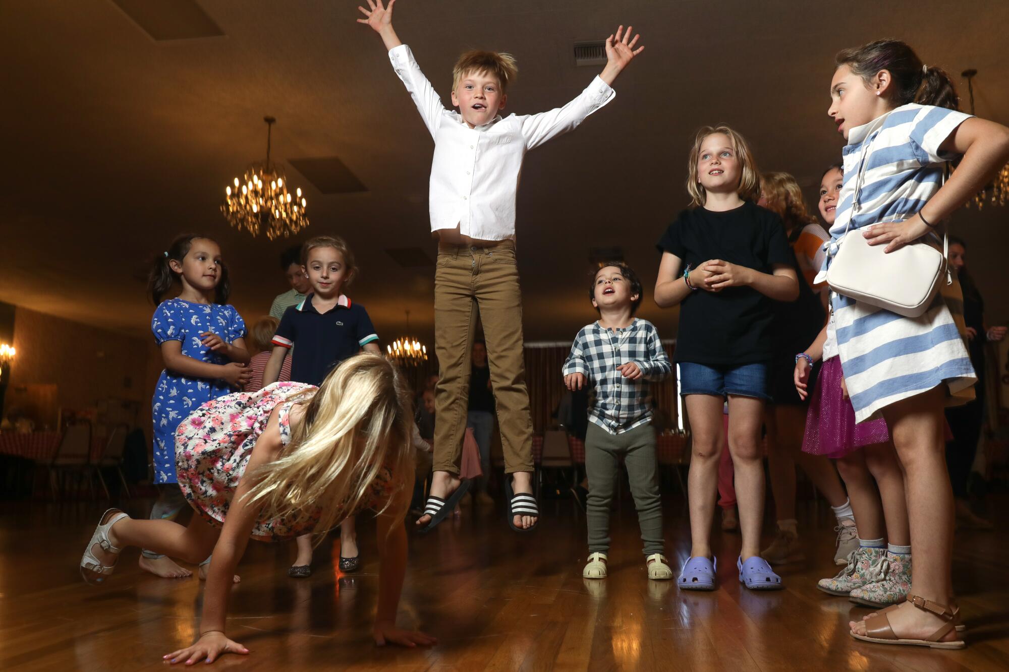 A child jumps while other kids dance and watch on the dance floor at the Garibaldina Society. 