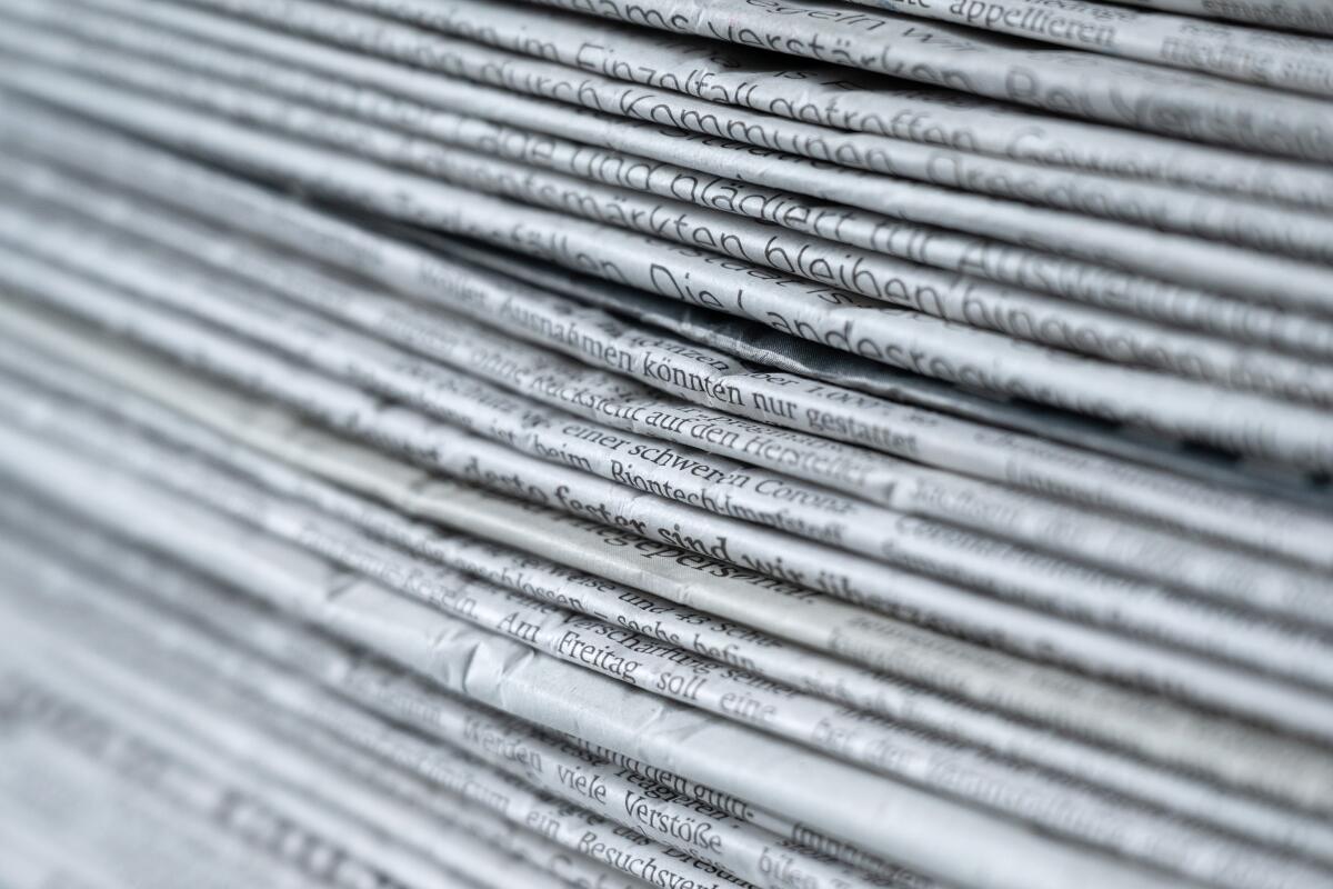 A side view of a stack of various newspapers